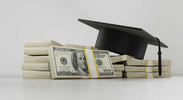 graduation cap on pile of cash